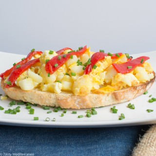 Tosta de huevos revueltos con patatas, cebolla y pimientos del piquillo